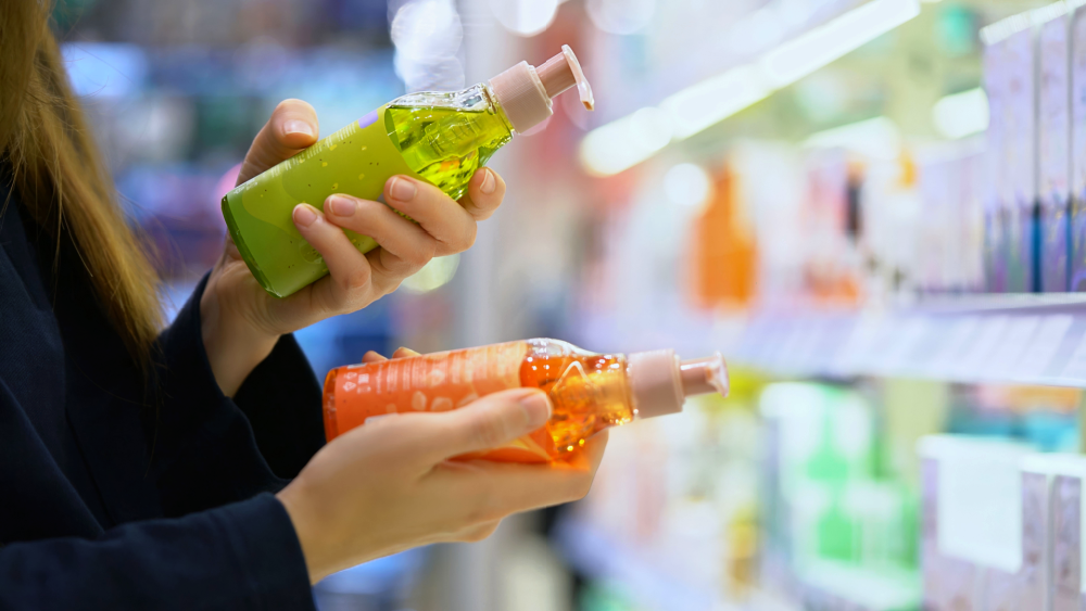 Forbruker sammenligner produkter med fargede emballasjer i butikkhylle