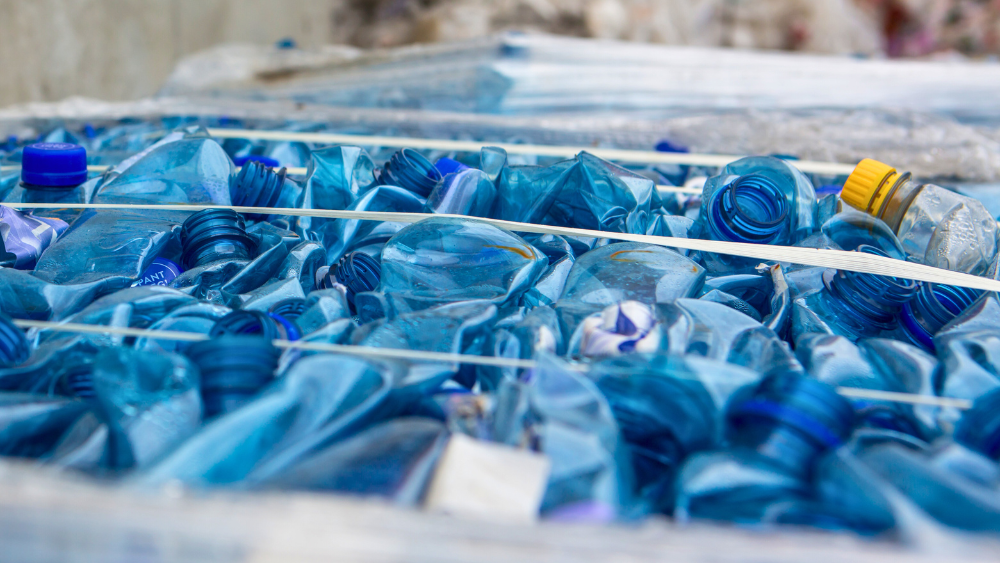 Sammenpressede blå plastflasker klare for gjenvinning.
