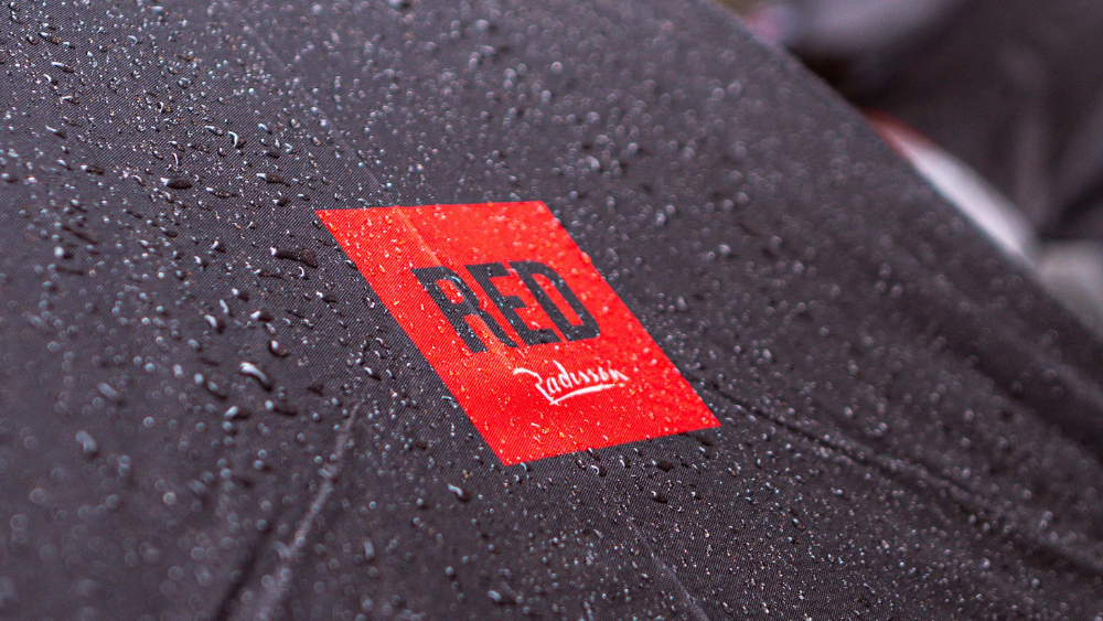 Nærbilde av paraply med Radisson RED-logo og regndråper.
