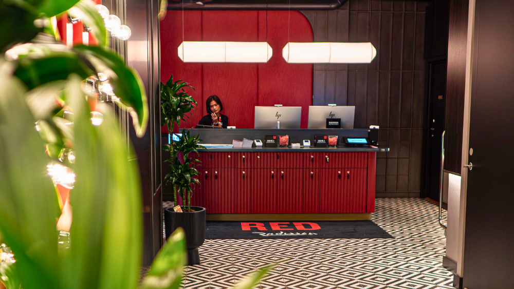 Resepsjonist i resepsjonsområdet på Radisson RED Oslo City Centre, med moderne design og røde detaljer.