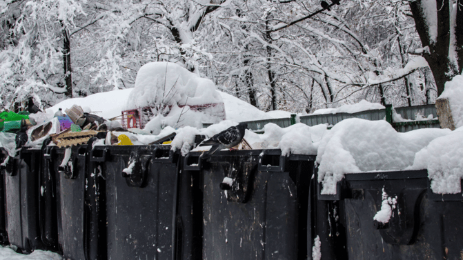 Avfallscontainere fylt med snø og avfall utendørs