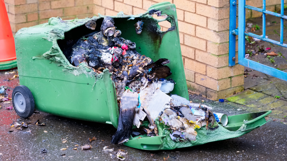 2.	Brannskadet grønn avfallsbeholder med forkullet innhold, smeltet plast og brente materialer.