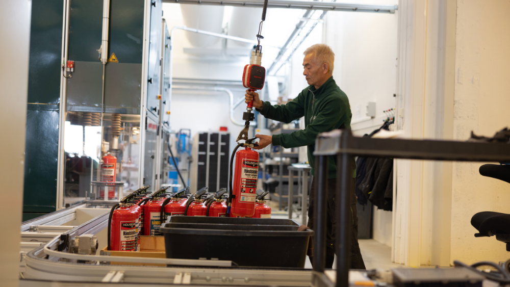 Ansatt kontrollerer brannslukker på produksjonslinje i fabrikk