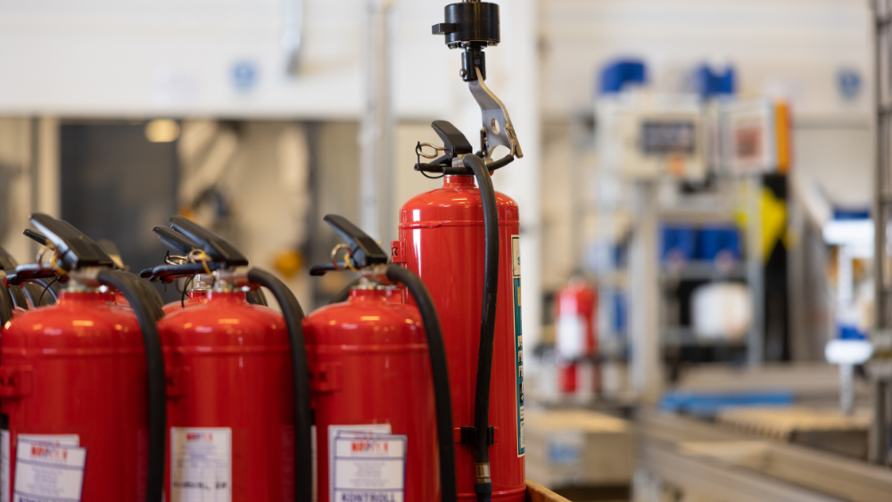 Røde brannslukkere på produksjonslinje i fabrikkmiljø