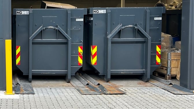 Avfallscontainerne i portåpning med skinnesystem i bakken.